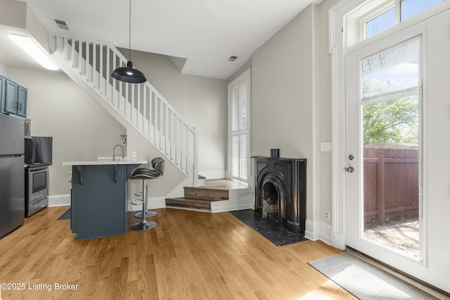 living room featuring visible vents, light wood-style flooring, and stairway