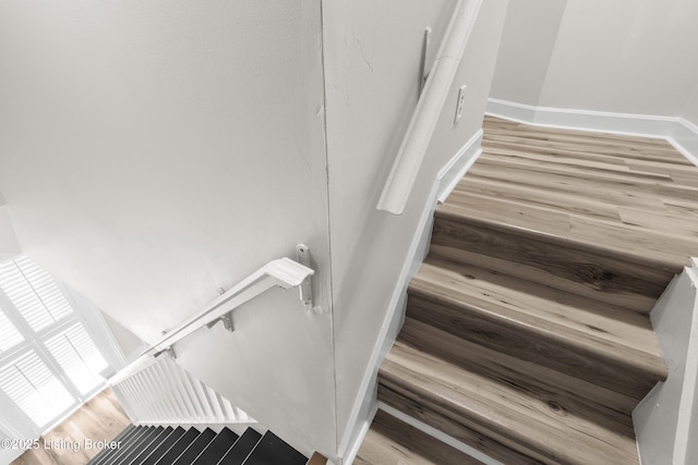 staircase featuring baseboards and wood finished floors