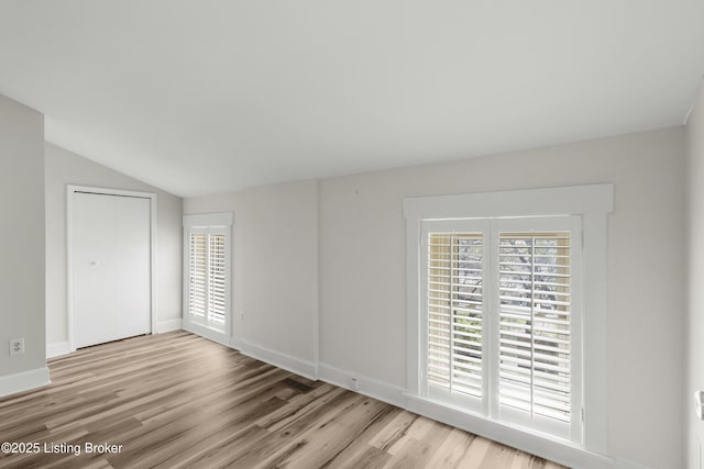unfurnished room featuring baseboards, vaulted ceiling, and wood finished floors