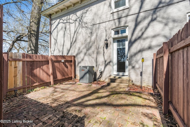 exterior space with central air condition unit, entry steps, a fenced backyard, and a patio area