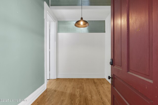 hallway featuring light wood-style flooring and baseboards