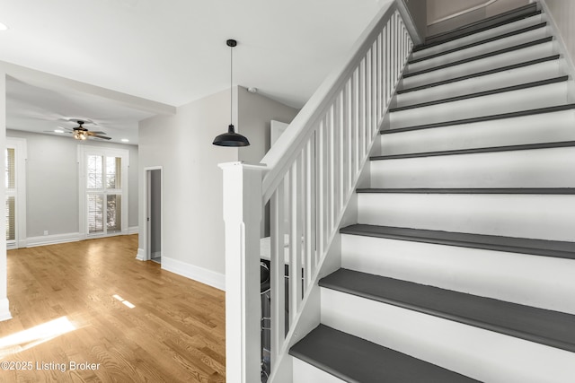 stairs featuring baseboards, a ceiling fan, and wood finished floors