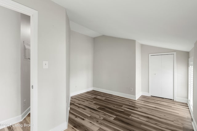 interior space with wood finished floors, baseboards, and vaulted ceiling