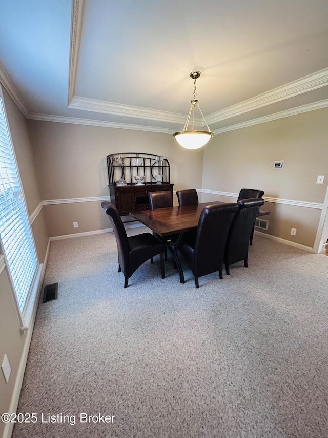 carpeted dining room featuring baseboards, crown molding, and visible vents
