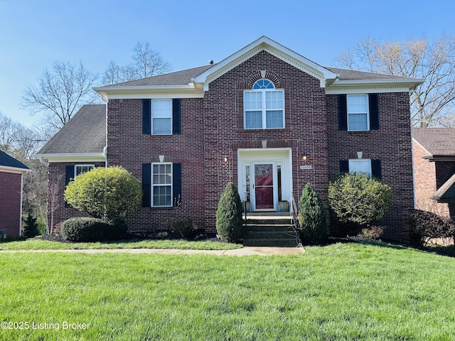 view of front of home with a front lawn, brick siding, and a shingled roof