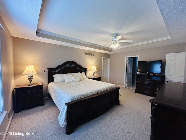 bedroom with ceiling fan, light carpet, a tray ceiling, baseboards, and visible vents