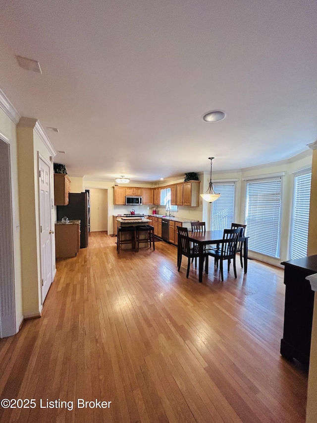 dining area featuring light wood finished floors and ornamental molding