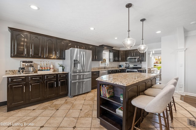 kitchen with appliances with stainless steel finishes, a breakfast bar, recessed lighting, and dark brown cabinetry