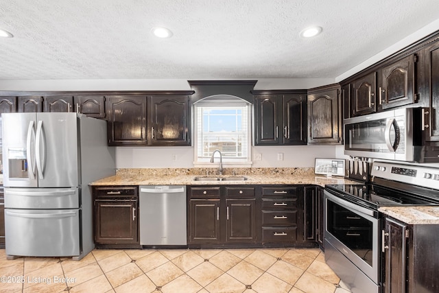 kitchen featuring arched walkways, a sink, dark brown cabinetry, a textured ceiling, and stainless steel appliances