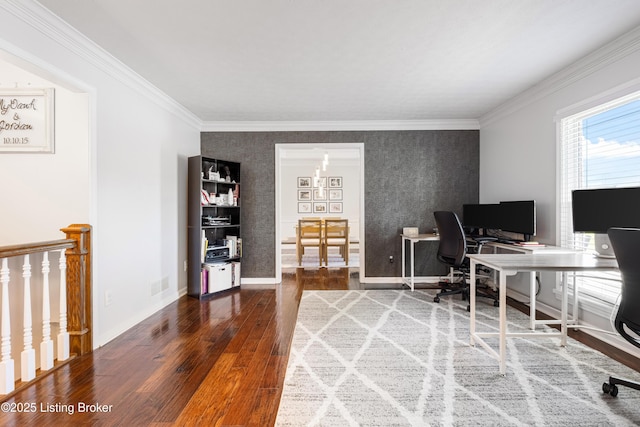 home office featuring wood-type flooring, an accent wall, visible vents, and ornamental molding