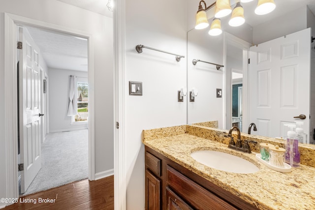 bathroom featuring a chandelier, baseboards, vanity, and wood finished floors