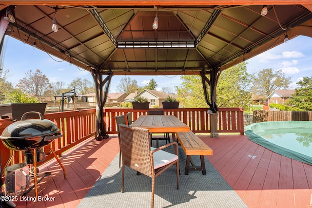 wooden terrace with a gazebo, outdoor dining area, and area for grilling