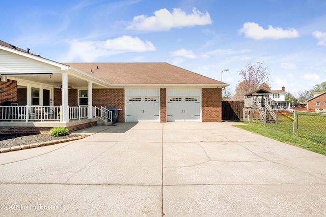 view of side of property featuring a porch, an attached garage, fence, concrete driveway, and brick siding