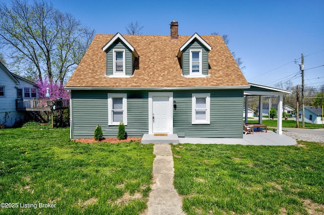 new england style home with roof with shingles, a chimney, and a front lawn