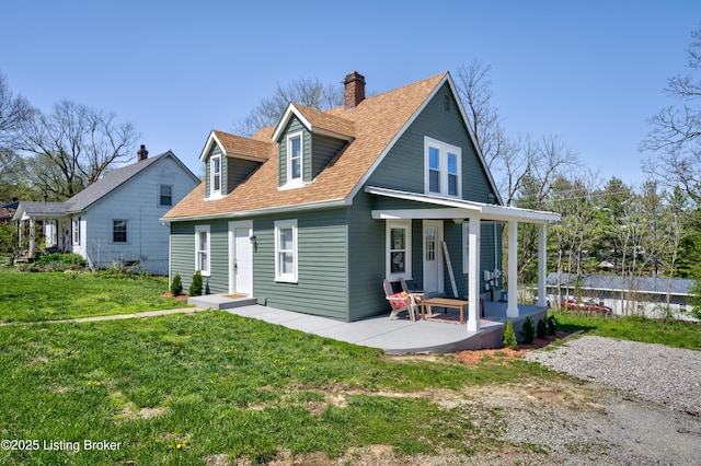 rear view of property with roof with shingles, a lawn, and a chimney