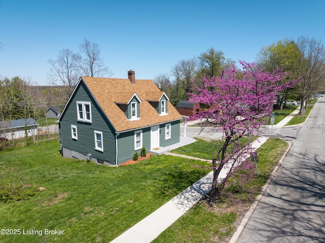 view of front of home featuring a chimney, a shingled roof, and a front lawn