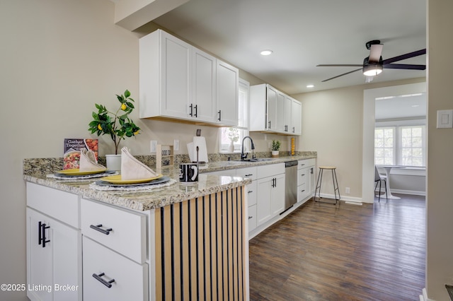 kitchen featuring dishwasher, a sink, dark wood-style flooring, a ceiling fan, and white cabinetry