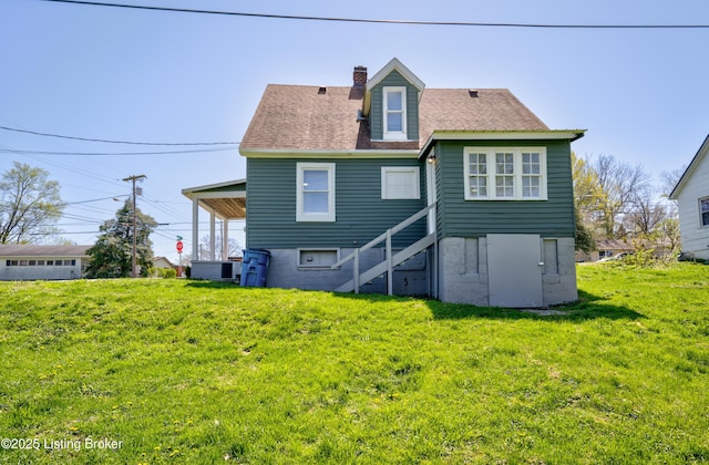 rear view of property with a yard, a chimney, and a shingled roof