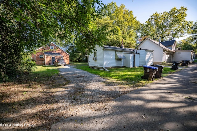 124 E Wellington Ave, Louisville, KY 40214 - view of home's exterior with driveway, an outdoor structure, and a lawn