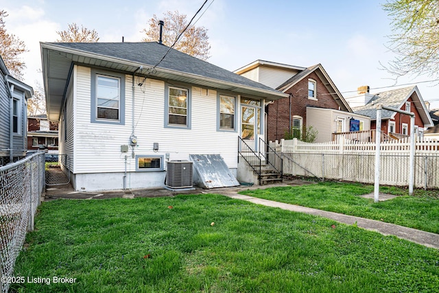 back of property featuring a fenced backyard, a shingled roof, cooling unit, and a lawn