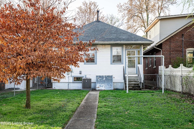 rear view of house featuring central AC unit, entry steps, a yard, fence, and a shingled roof