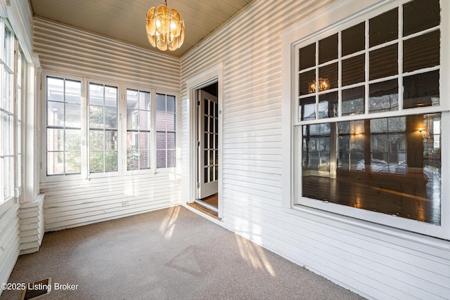 unfurnished sunroom featuring a notable chandelier and carpet floors