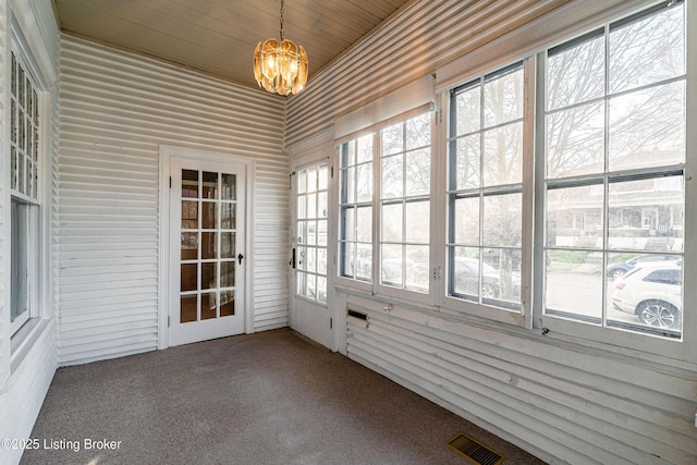 unfurnished sunroom featuring carpet flooring, visible vents, and an inviting chandelier