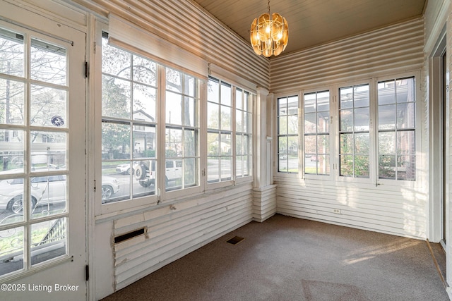 unfurnished sunroom with a notable chandelier, carpet flooring, and visible vents