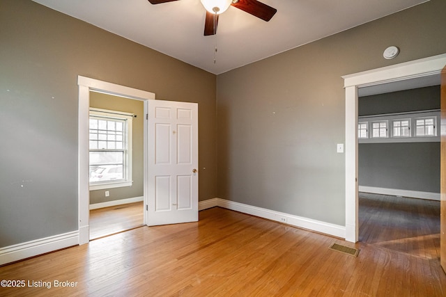 empty room featuring visible vents, baseboards, wood finished floors, and ceiling fan