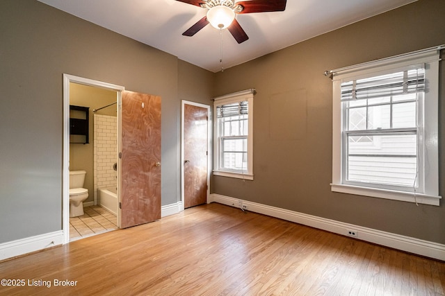 unfurnished bedroom featuring light wood-style flooring, ensuite bath, and baseboards