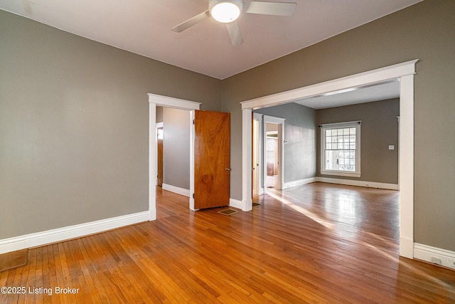 unfurnished room featuring visible vents, wood-type flooring, ceiling fan, and baseboards