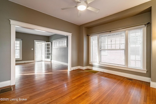 empty room with visible vents, baseboards, hardwood / wood-style floors, and ceiling fan
