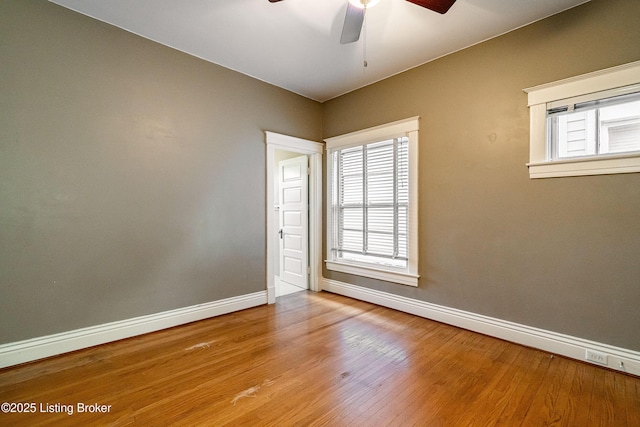 empty room with wood finished floors, baseboards, and a ceiling fan