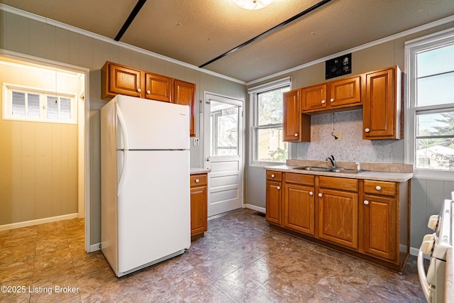 kitchen featuring brown cabinetry, stove, a sink, and freestanding refrigerator