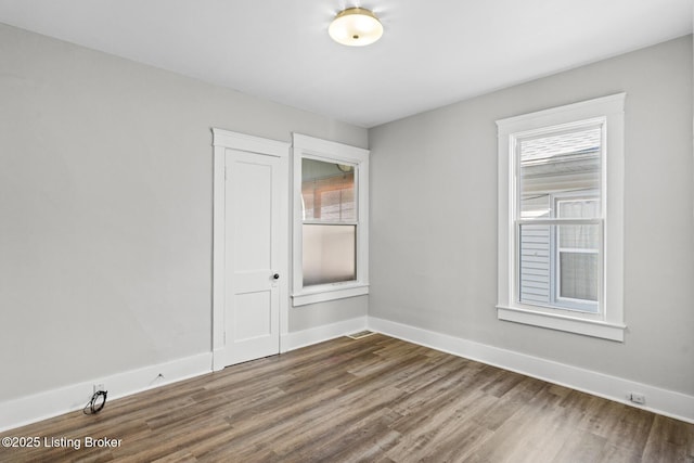 unfurnished room with dark wood-style flooring, baseboards, and a healthy amount of sunlight