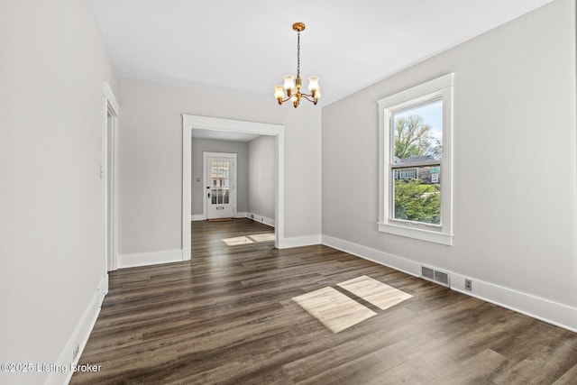 unfurnished dining area featuring dark wood-style floors, baseboards, an inviting chandelier, and visible vents