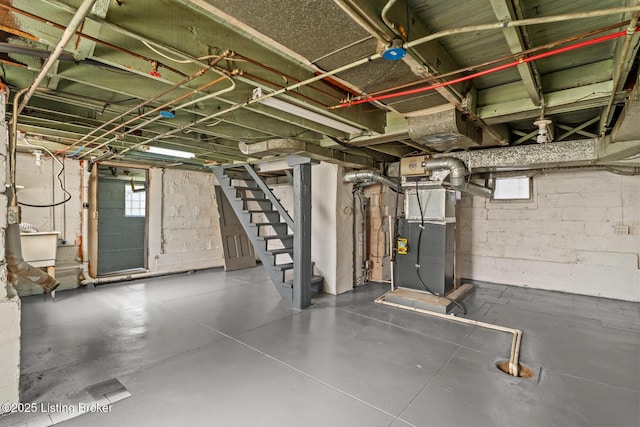 basement with heating unit, plenty of natural light, and stairs