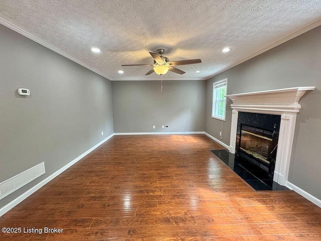 unfurnished living room with crown molding, a textured ceiling, visible vents, and wood finished floors