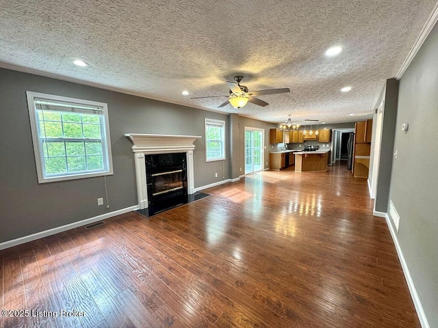 unfurnished living room featuring crown molding, baseboards, ceiling fan with notable chandelier, and a high end fireplace