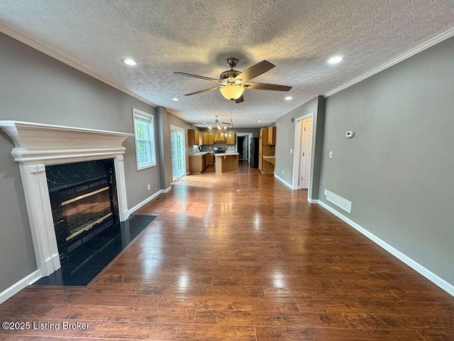 unfurnished living room featuring a ceiling fan, a premium fireplace, dark wood finished floors, visible vents, and ornamental molding