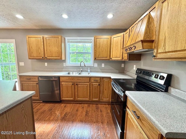 kitchen with a sink, dark wood-type flooring, light countertops, electric range, and stainless steel dishwasher