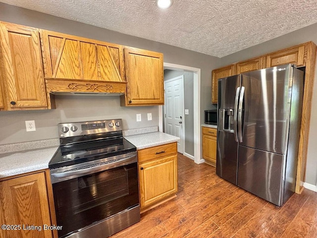 kitchen with stainless steel appliances, light countertops, baseboards, and dark wood finished floors