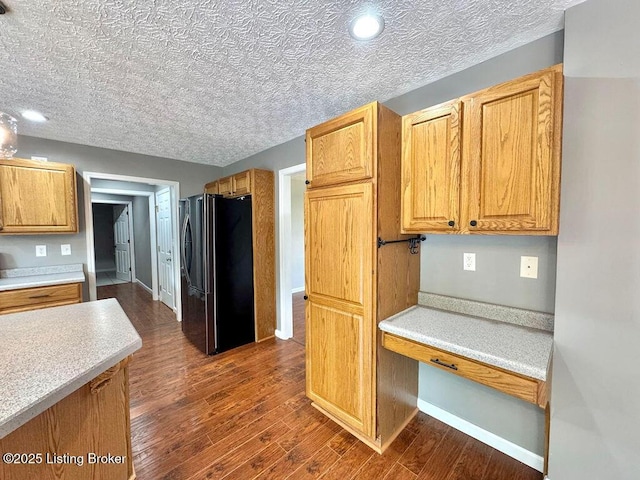 kitchen with freestanding refrigerator, light countertops, dark wood finished floors, and baseboards