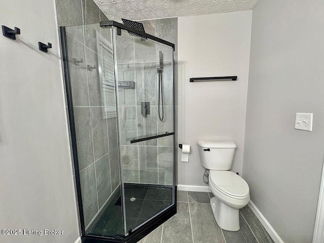 bathroom with toilet, a stall shower, tile patterned floors, a textured ceiling, and baseboards
