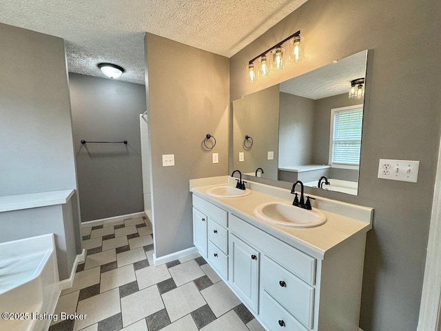 bathroom featuring a sink, double vanity, a textured ceiling, and baseboards