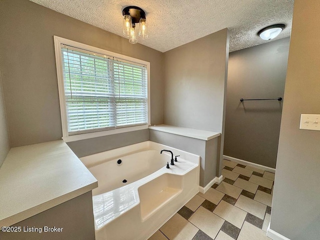 bathroom featuring a textured ceiling, a garden tub, baseboards, and tile patterned floors