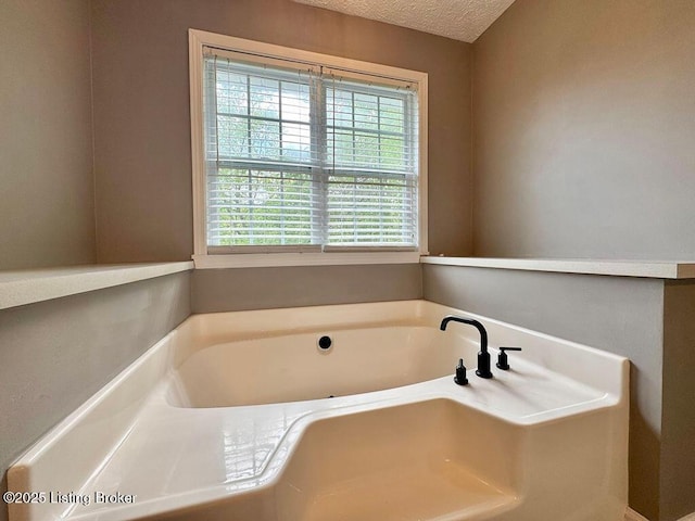 bathroom featuring a garden tub and a textured ceiling