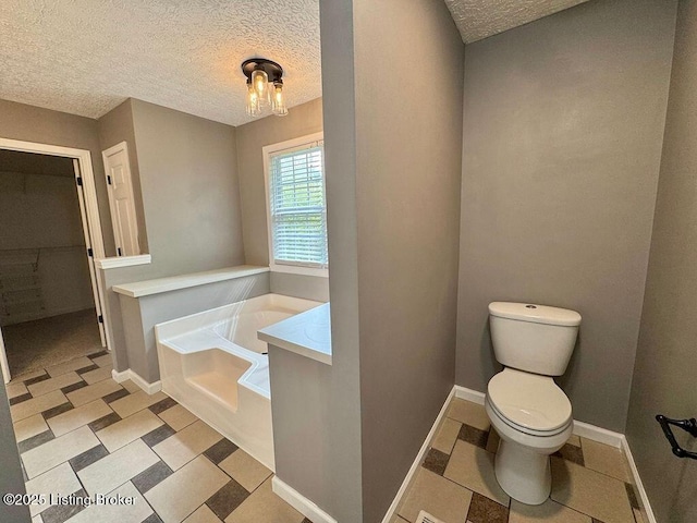 bathroom featuring a textured ceiling, a garden tub, toilet, and baseboards