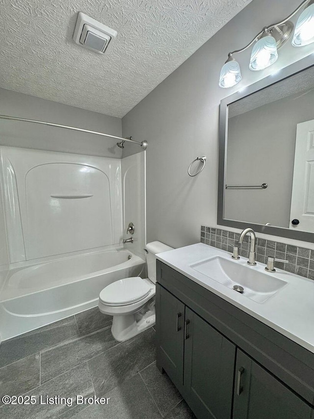 full bath with a textured ceiling, toilet, visible vents, vanity, and washtub / shower combination