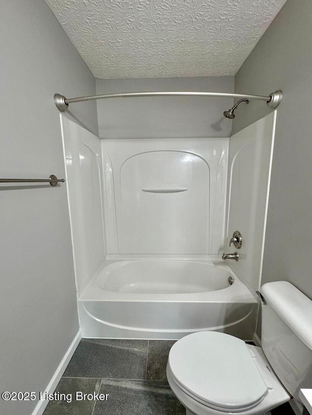 bathroom with toilet, baseboards, bathtub / shower combination, and a textured ceiling